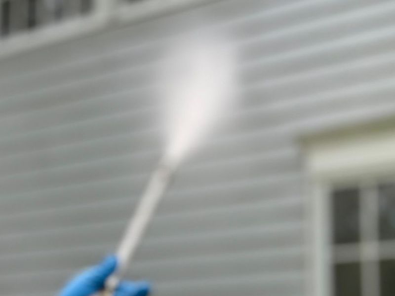 Close-up of a pressure washer spray on house siding (representative stock photo)